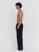 A male model, in profile, wears black wide-leg sweatpants by One Dna brand