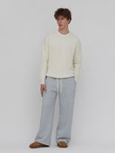 A model wears men's cream cable knit  sweater by One Dna brand